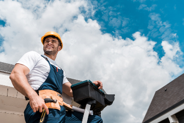 low angle view of happy repairman in helmet holding hammer and toolbox